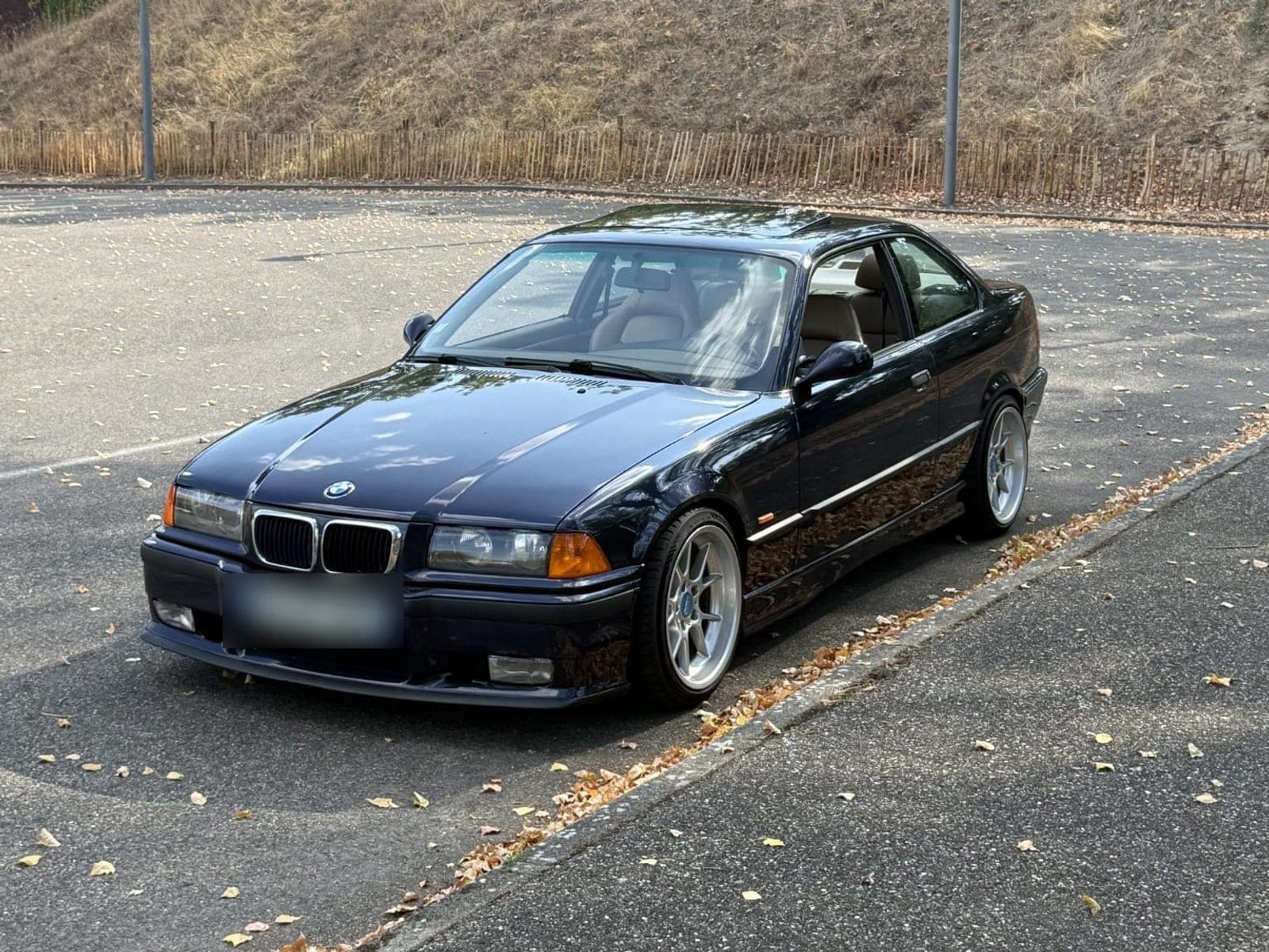 BMW Série 3 E36 328i coupé bleu nuit, vue de trois-quarts avant, plaque masquée par Flyvo