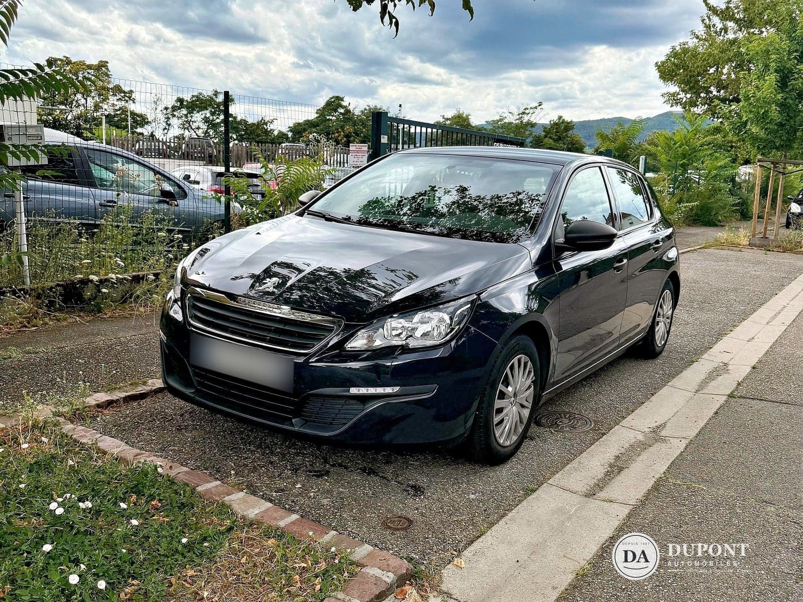 La même Peugeot 308 après traitement par Flyvo : lumière corrigée, plaque floutée, logo du garage en filigrane